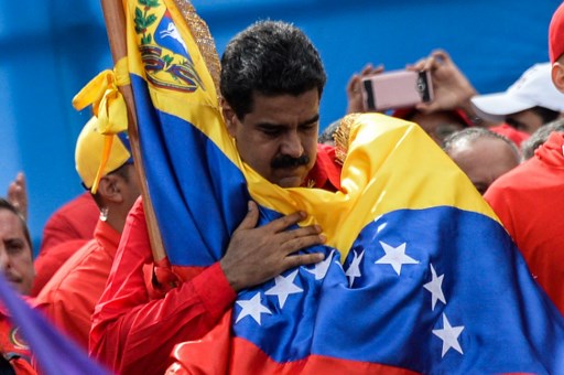 El Presidente de Venezuela, Nicolás Maduro sostiene la bandera nacional. Durante el domingo informó de una revuelta que fue aplacada en la tercera ciudad más poblada del país sudamericano. / AFP PHOTO / Federico PARRA