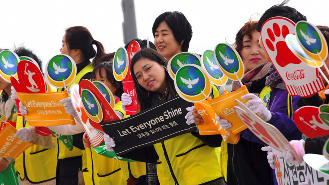 (FILES) This file photo taken on November 01, 2017 shows people waving banners reading "Let Everyone Shine," during a ceremony of the start the Olympic torch relay across South Korea at Incheon bridge, west of Seoul. South Korea is ready to welcome the world at the 2018 Winter Olympics, including athletes from its sabre-rattling neighbour North Korea, chief organiser Lee Hee-Beom said in Prague on November 3, 2017. JUNG Yeon-Je / AFP