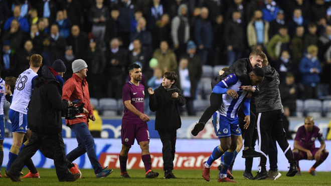 Manchester City's Argentinian striker Sergio Aguero (C) walks as supporters invade the pitch after the English FA Cup fifth round football match between Wigan Athletic and Manchester City at the DW Stadium in Wigan, northwest England, on February 19, 2018. Oli SCARFF / AFP