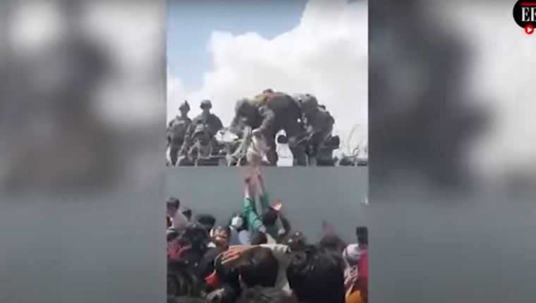 Un bebé afgano es entregado por encima de un muro en Kabul a soldados de EE. UU.