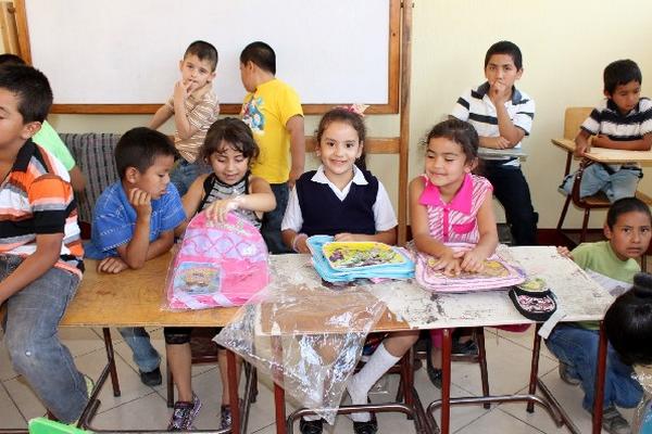 Estudiantes muestran su alegría al recibir una mochila con útiles escolares.
