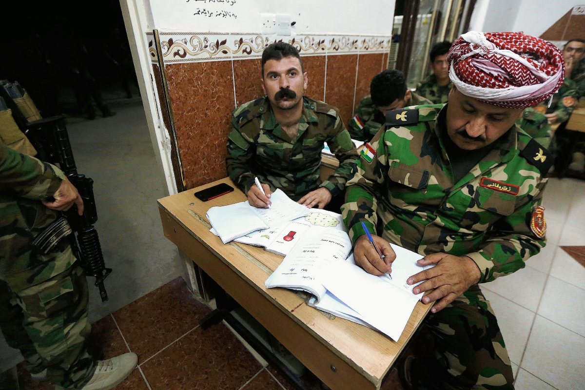Un combatiente kurdo peshmerga asiste a clases y escribe lo que el profesor anota en la pizarra. Los militantes kurdos aprenden a leer y escribir una vez que termina una jornada de combates contra el Estado Islámicoa. (Foto Prensa Libre: AFP).