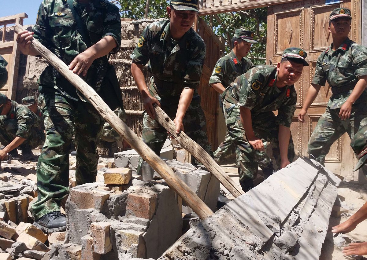 Militares chinos levantan los escombros de una vivienda que se derrumbó en la provincia de Xinjiang. (Foto Prensa Libre: AFP).