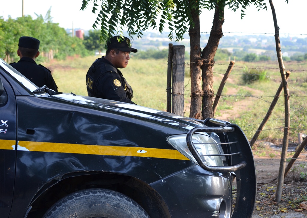 Agentes de la PNC custodian el lugar donde fueron hallados los cuerpos quemados de dos hombre. (Foto Prensa Libre: Edwin Paxtor)