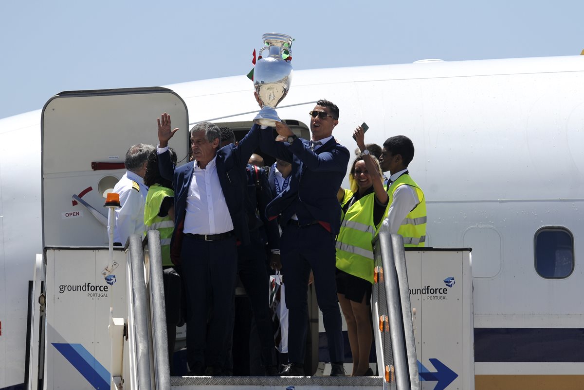 La estrella portuguesa Cristiano Ronaldo levanta el trofeo de la Eurocopa antes de abordar el vuelo que trasladó a la selección a territorio luso. (Foto Prensa Libre: AFP)