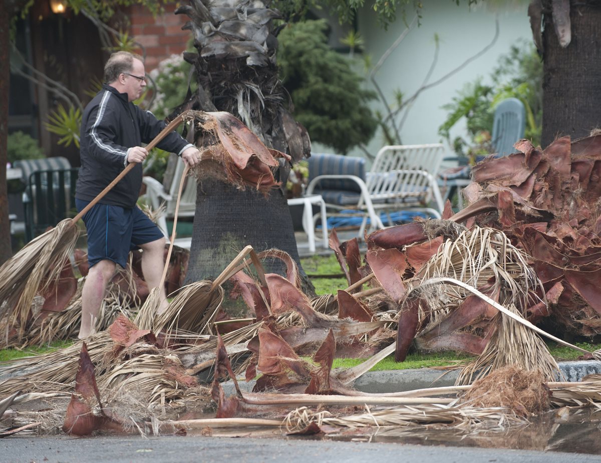 Un hombre limpia el frente de su vivienda luego del fuerte viento en California. (Foto Prensa Libre: AP).