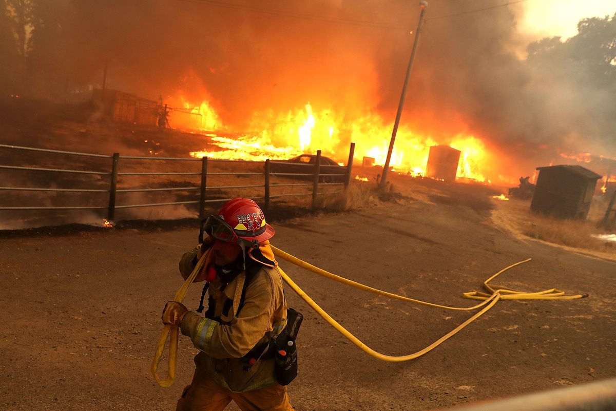 Un bombero saca la manguera de un establo que se quemó por el incendio en Lakeport, California.(AFP)