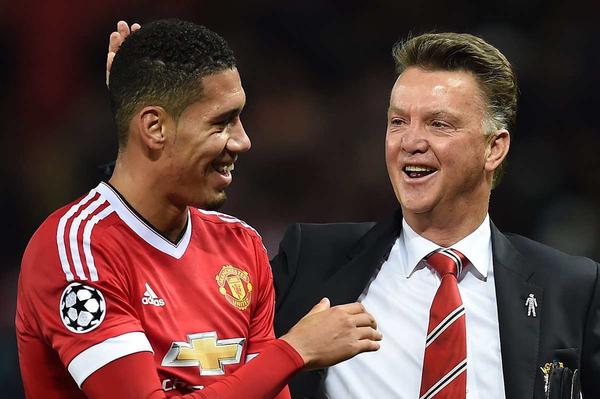 Louis van Gaal volvió a sonreir en la Champions mientras bromea con Chris Smalling. (Foto Prensa Libre: AFP)