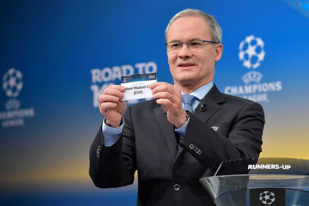 El director de competición de la Uefa, Giorgio Marchetti, muestra la papeleta del Real Madrid durante el sorteo de octavos de final de la Champions League. (Foto Prensa Libre: AFP)