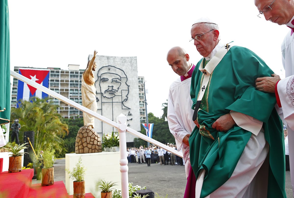 El papa Francisco sube al altar donde ofició la misa en la Plaza de la Revolución; al fondo, la bandera cubana y la imagen del "Che" Guevara. (Foto Prensa Libre: AP).