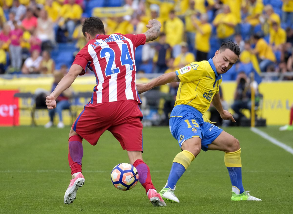 El defensa uruguayo del Atlético de Madrid José María Giménez (i) disputa un balón con el centrocampista de Las Palmas Roque Mesa. (Foto Prensa Libre: EFE)