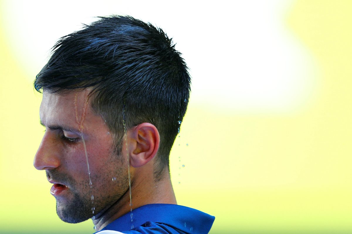 Novak Djokovic se refresca durante un descanso del partido ante el francés Gael Monfils en la segunda ronda del Abierto de Australia. (Foto Prensa Libre: EFE)