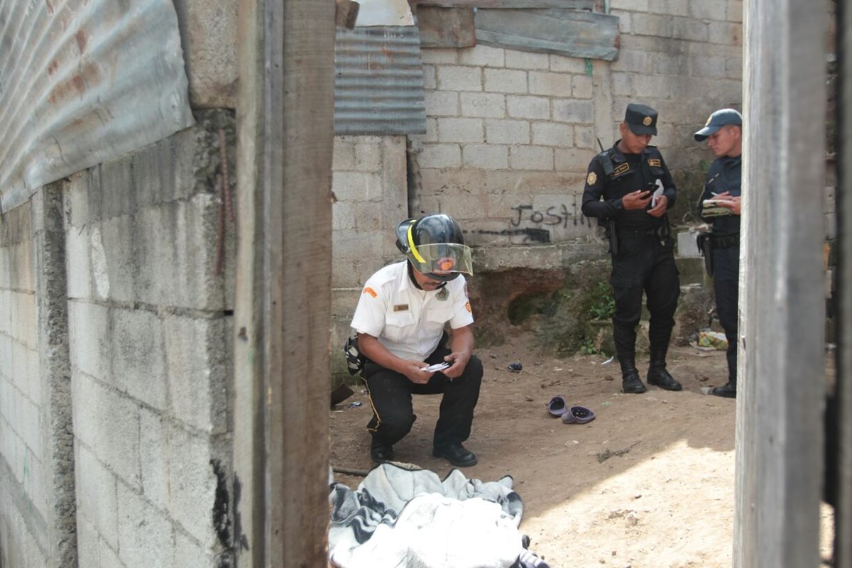 Un bombero voluntarios cubre el cadáver de Alonzo Suruy, luego de confirmar la muerte por lesiones de bala. (Foto Prensa Libre: Erick Avila)