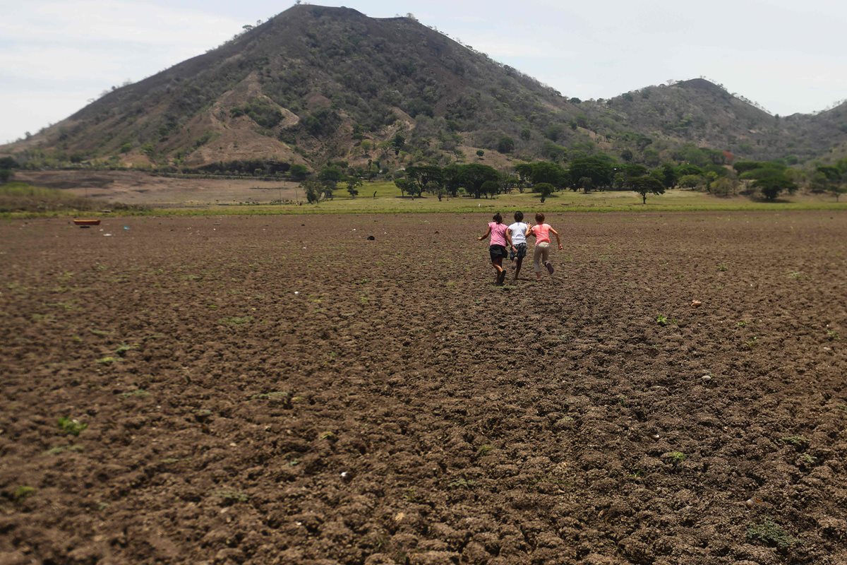 Un grupo de niños corre sobre el terreno árido de lo que en algún momento fue la Laguna de Atescatempa, Jutiapa. (Foto Prensa Libre: AFP)