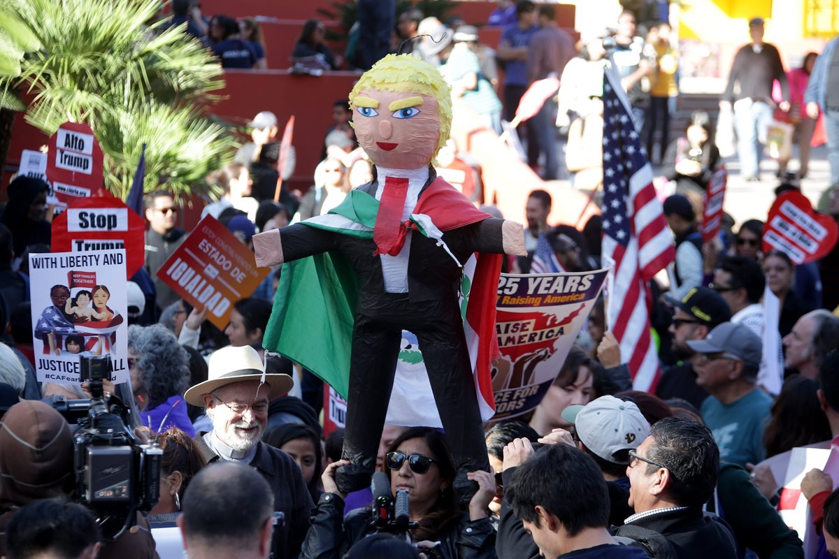 Latinos portan una piñata con la figura del presidente electo de EE. UU., Donald Trump, durante la marcha en Los Ángeles. (Foto Prensa Libre: EFE).