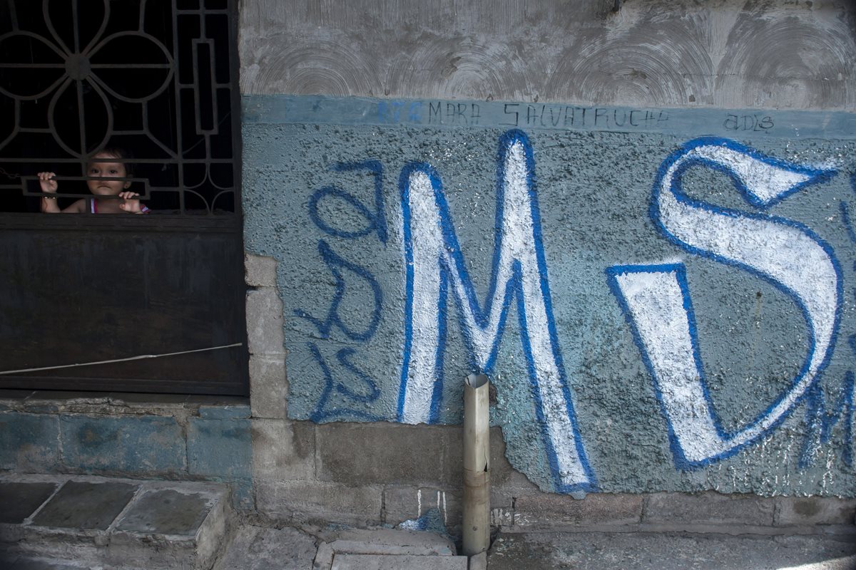 Una niña observa en la puerta de una vivienda que fue pintada por pandilleros en Soyapanago, El Salvador. (Foto Prensa Libre: AP).