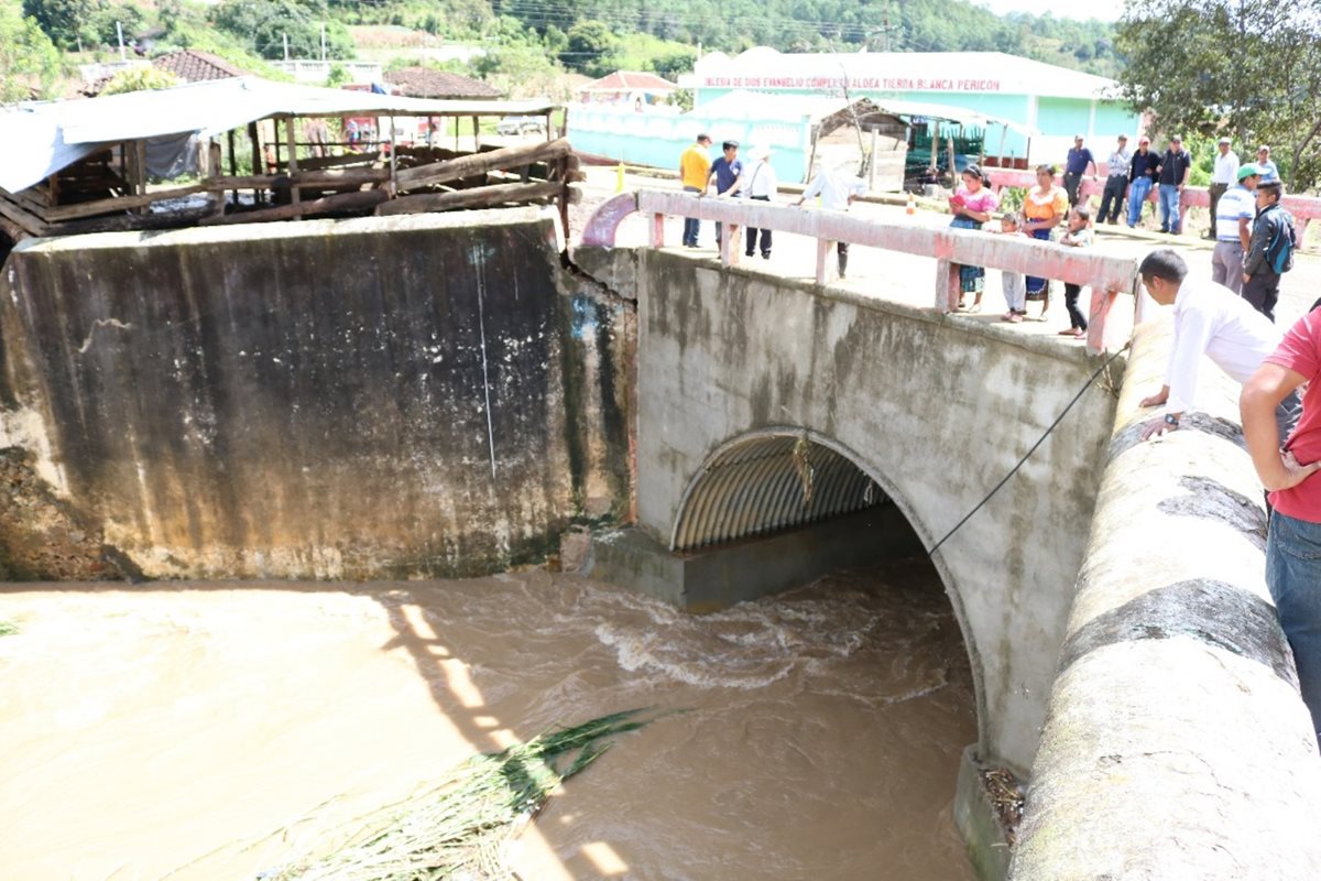 Un grupo de pobladores ven los daños que tiene una parte de la estructura del puente Negro. (Foto Prensa Libre: Héctor Cordero)