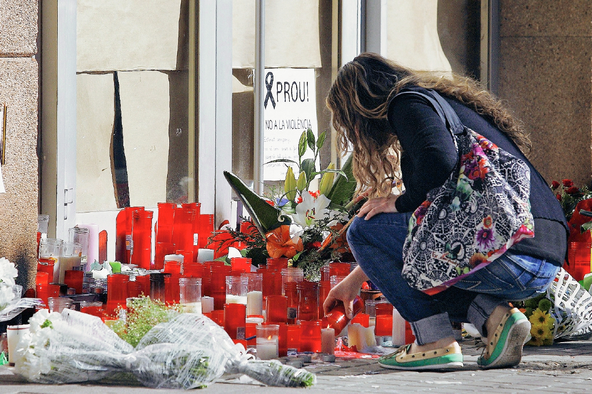 Una mujer enciende una vela en memoria del profesor asesinado por el menor. (Foto Prensa Libre: AFP).