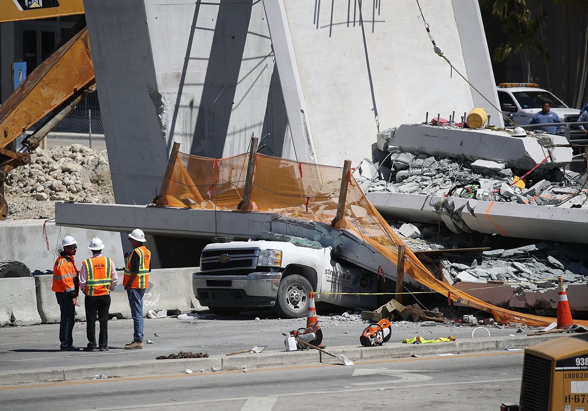 Trabajadores investigan la escena donde un puente peatonal se derrumbó en Miami. (AFP).