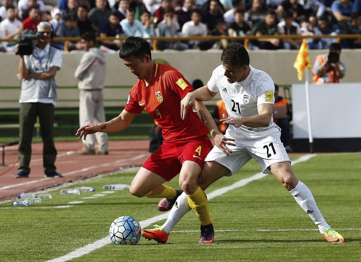 Jiang Zhipeng trata de quedarse con el balón ante la marca de Vorya Ghafuri durante el partido clasificatorio para la Copa del Mundo de Rusia 2018 entre Irán y China. (Foto Prensa Libre: EFE)