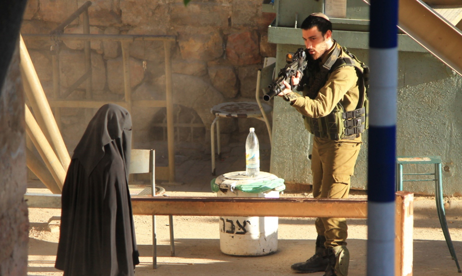 Un soldado israelí apunta con su arma a una mujer palestina. (Foto Prensa Libre: AP).