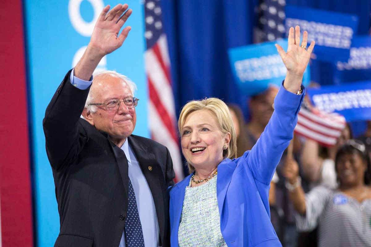 El senador Bernie Sanders (i), saluda a los simpatizantes mientras abraza a la virtual candidata demócrata Hillary Clinton (i). (Foto Prensa Libre: AP).