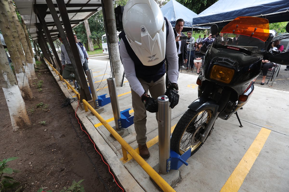 Un estudiante introduce la llave electrónica en el parquímetro y usa el sujetador para retener la motocicleta. (Foto Prensa Libre: Estuardo Paredes)