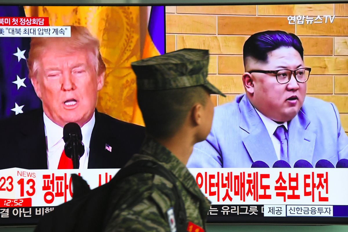Un soldado surcoreano pasa frente a una pantalla de televisión que muestra imágenes del presidente estadounidense, Donald Trump (L) y el líder norcoreano, Kim Jong Un, en una estación de tren en Seúl.(AFP).