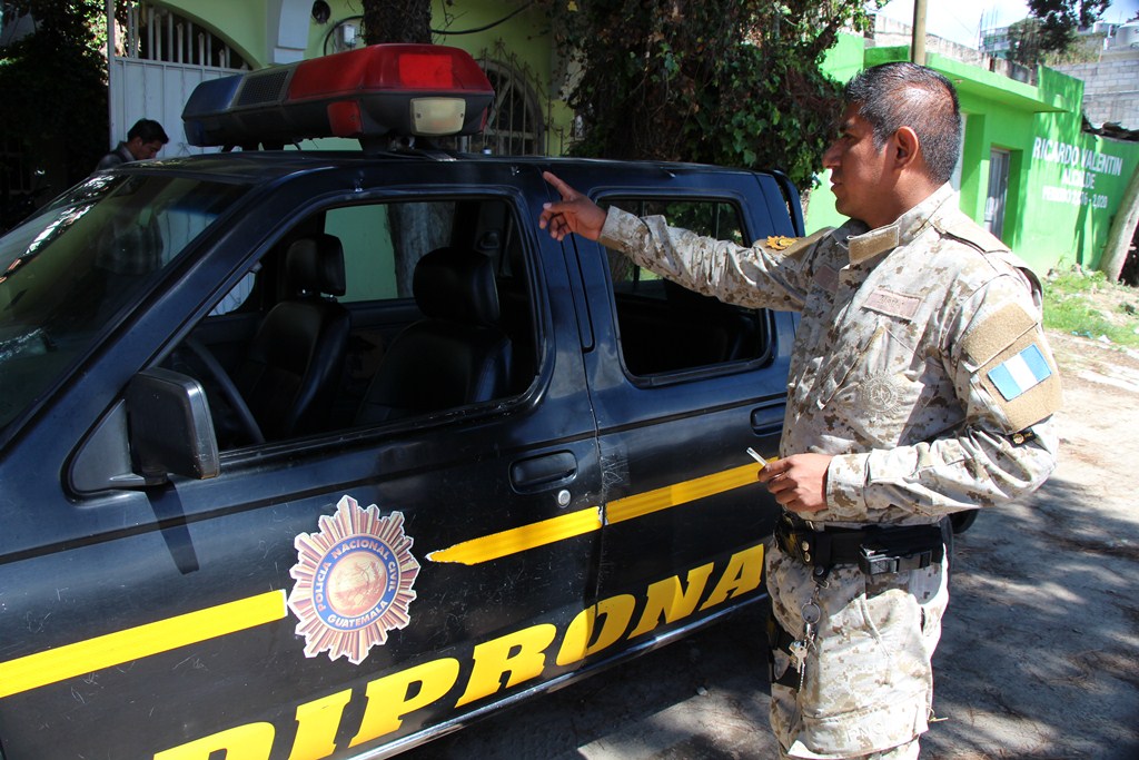 Agente de la Diprona muestra algunos de los daños que la turba causó a un autopatrulla en San Cristóbal Totonicapán. (Foto Prensa Libre: Édgar Domínguez)