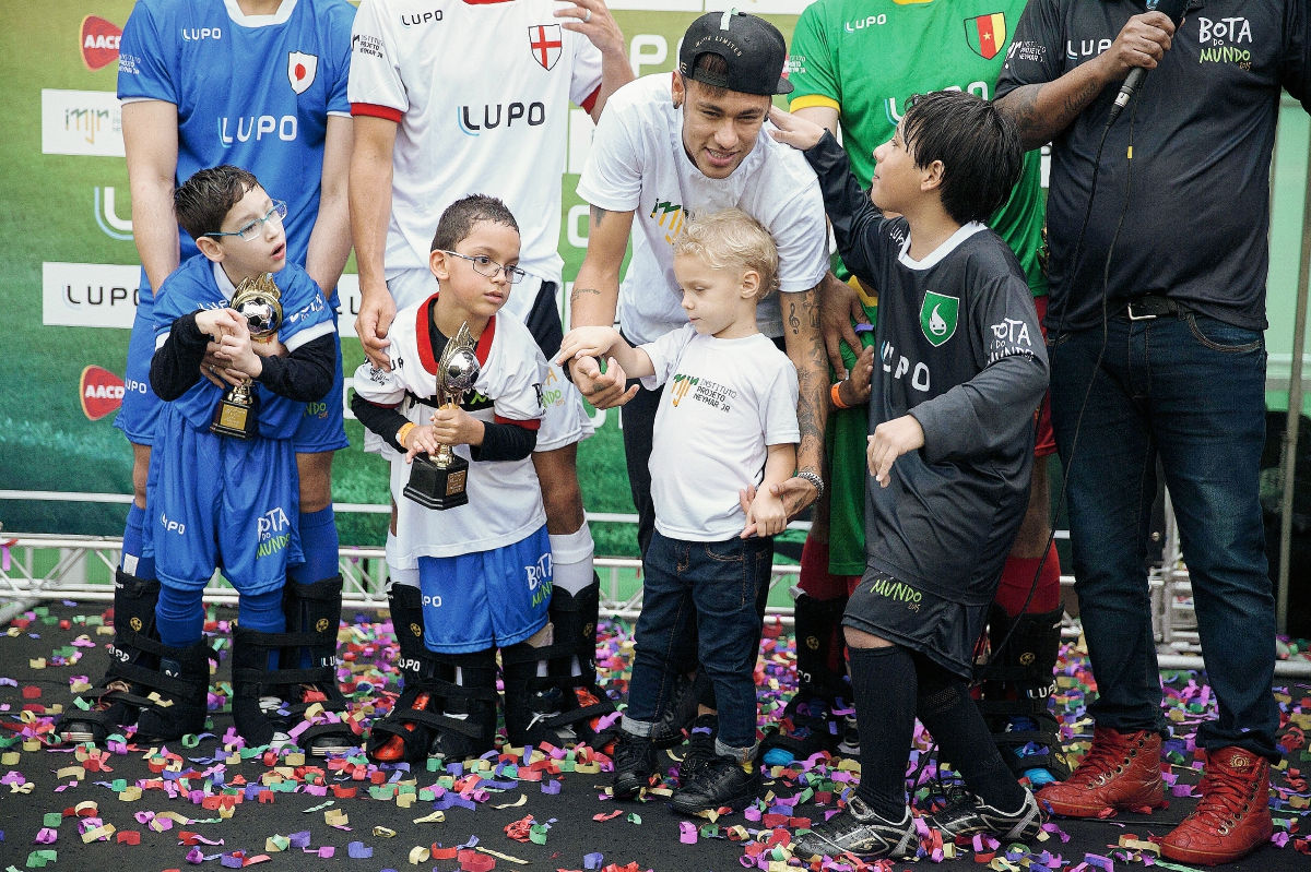 El delantero brasileño Neymar Jr., acompañado de su hijo Davi Lucca, asiste a un evento con niños discapacitados este martes, en Praia Grande (Brasil), en el campo de futbol del Instituto Neymar Jr. (Foto Prensa Libre: EFE)