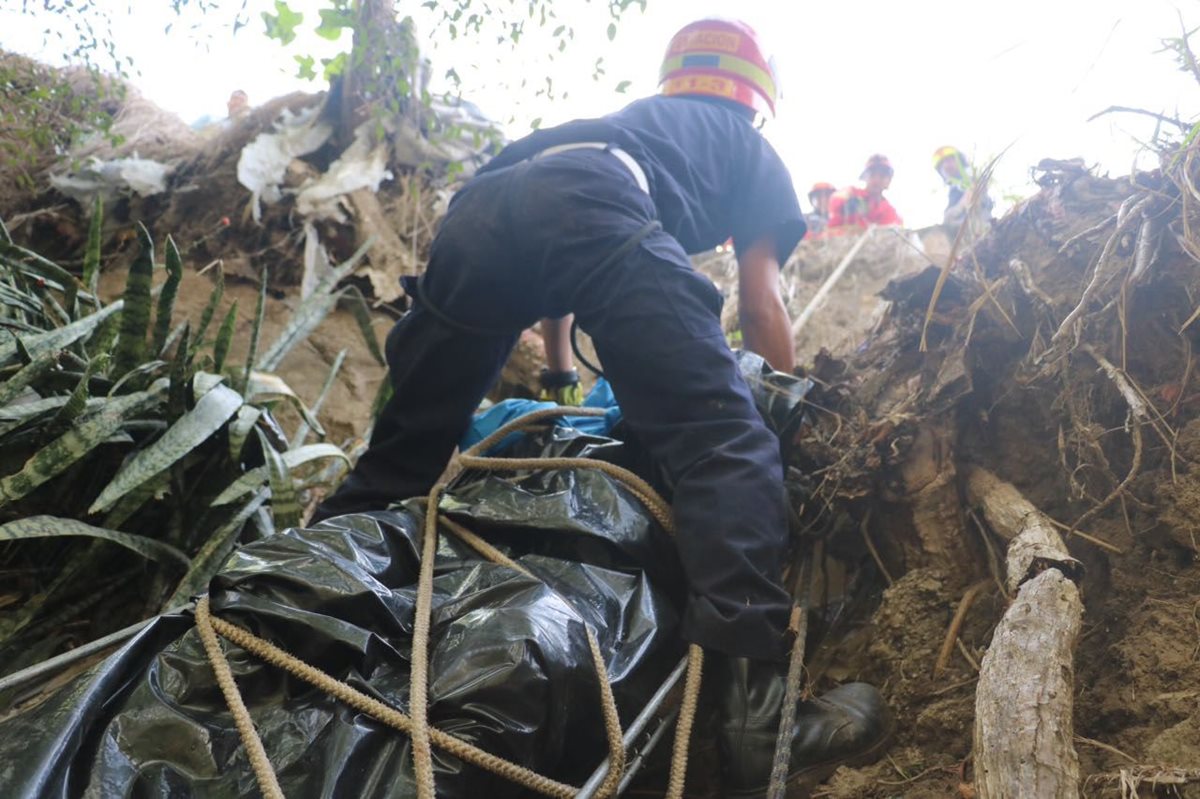 Un bombero sube con el cadáver a la orilla de la carretera. (Foto Prensa Libre: CBM)