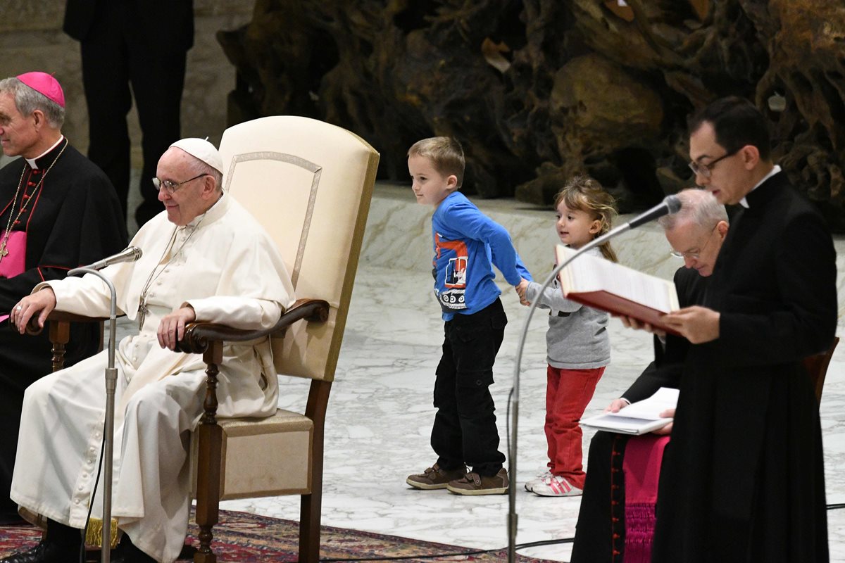 El pequeño Wenzel Eluney  junto a su hermana, juegan detrás del Papa Francisco.