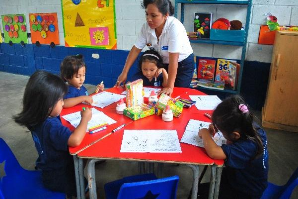 Una de  las cuatro maestras atiende a un grupo de niños.