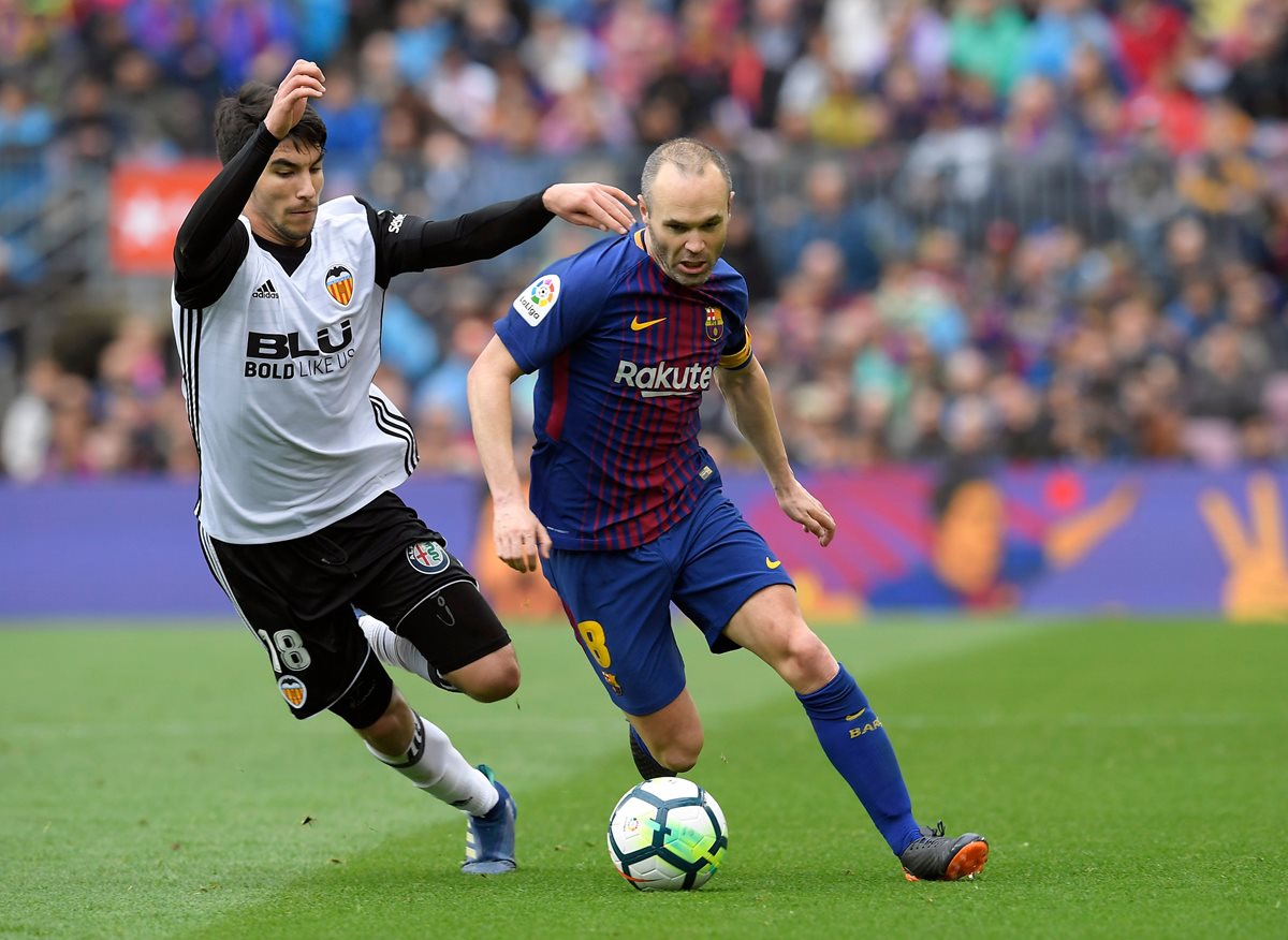 Carlos Soler trata de detener a Andrés Iniesta durante el partido entre el Barcelona y Valencia. (Foto Prensa Libre: AFP)