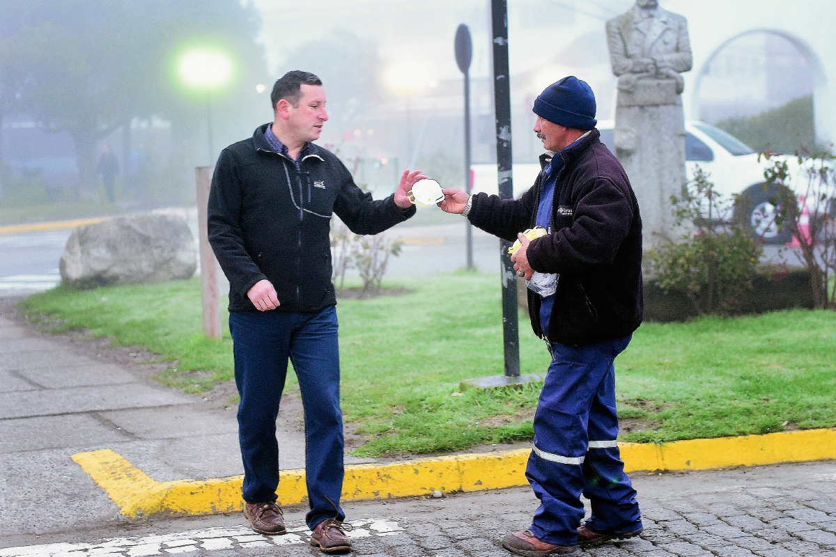 Un socorrista distribuye mascarillas para protegerse de la ceniza volcánica. (Foto Prensa Libre: AFP).