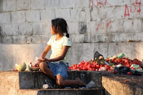 Una niña se alimenta con frutas encontradas en el vertedero del mercado La Terminal, de Reu.