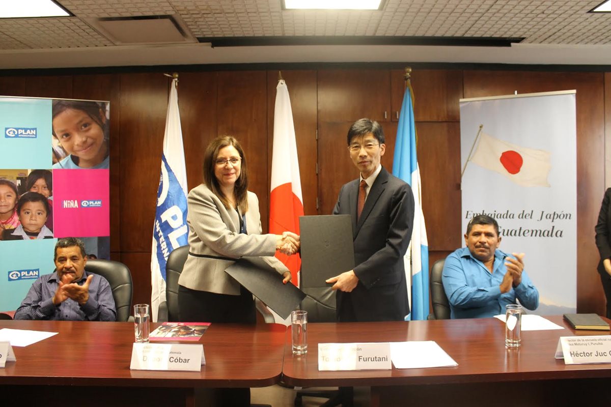 Débora Cóbar, directora de Plan Internacional, y Tomohiko Furutani, embajador del Japón, -al centro- luego de la firma del convenio de cooperación. (Foto Prensa Libre: Cortesía).