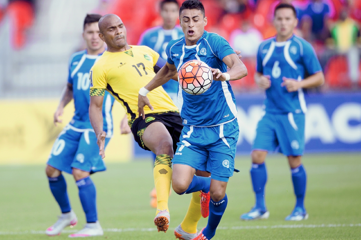 Rudolph Austin de Jamaica y Darwin Ceren, de El Salvador, luchan por un balón en el encuentro de este martes. (Prensa Libre: AFP)