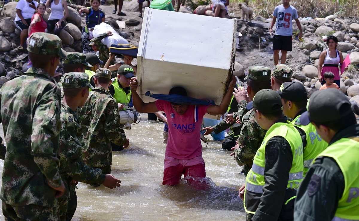 Un hombre cruza el río Táchina enla frontera colombo-venezolana, con un electrodoméstico en su espalda, luego de ser deportado. (Foto Prensa Libre: AFP).