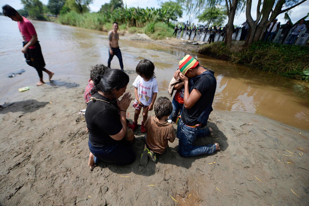 Una familia de migrantes hondureños ora en su trayecto hacia México y Estados Unidos. (Foto Prensa Libre: AFP)