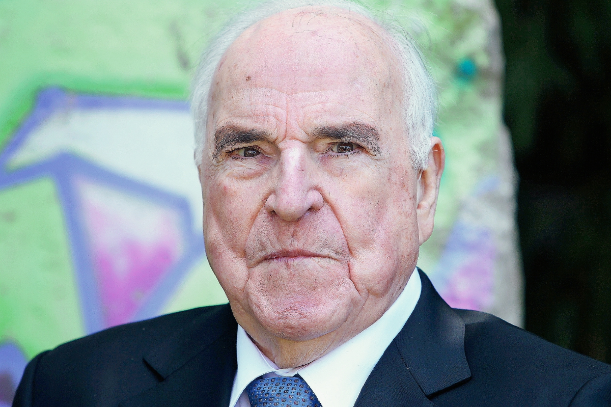 El excanciller alemán Helmut Kohl posan delante de un trozo del muro de Berlín en el jardín de su casa en Oggersheim cerca de Ludwigshafen, Alemania. (Foto Prensa Libre:AFP).