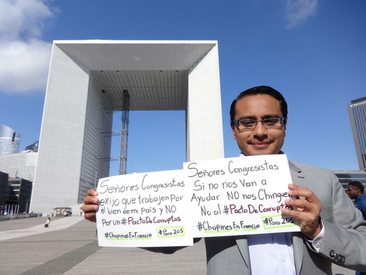 Un guatemalteco en Francia sostiene unos carteles con consignas que apoyan el paro nacional. (Prensa Libre Foto: Cortesía)