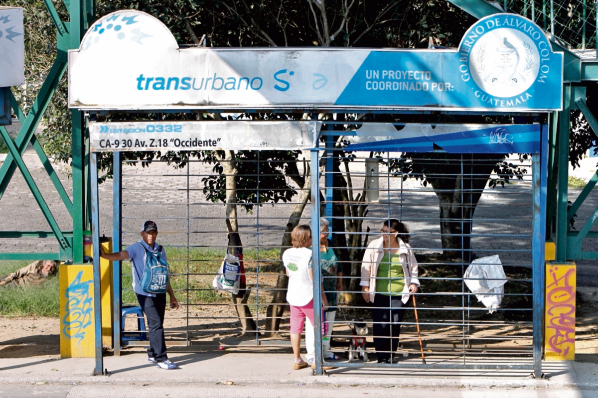 Sin resguardo de agentes de seguridad privada, personas esperan la llegada de un bus en la carretera al Atlántico, zona 18.