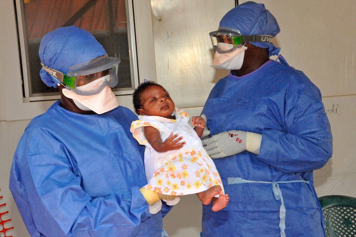 Enfermeros cargan a Nubia, una bebé que fue la última persona infectada con ébola en Guinea y que ya ha sanado. (Foto Prensa Libre: AFP).