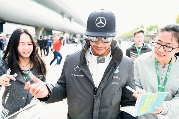 Lewis Hamilton firma autógrafos a sus seguidoras tras la segunda practica del GP de China. (Foto Prensa Libre: AFP).