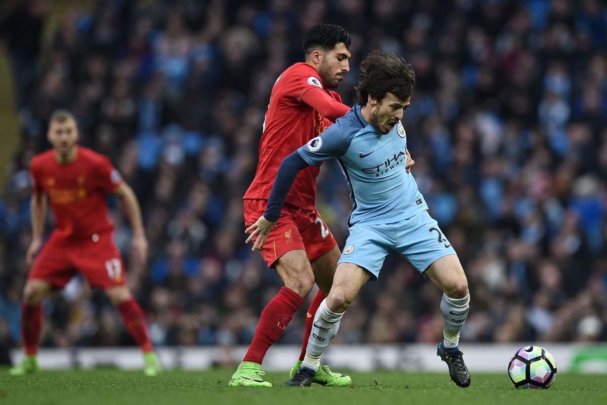 Emre Can trata de quitarle el balón a David Silva. (Foto Prensa Libre: AFP)