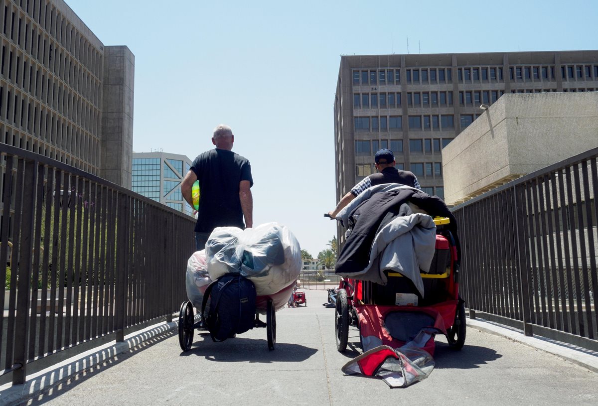 Dos hombres sin techo salen con un carrito con sus pertenencias en el Condado de Orange, California. (EFE).