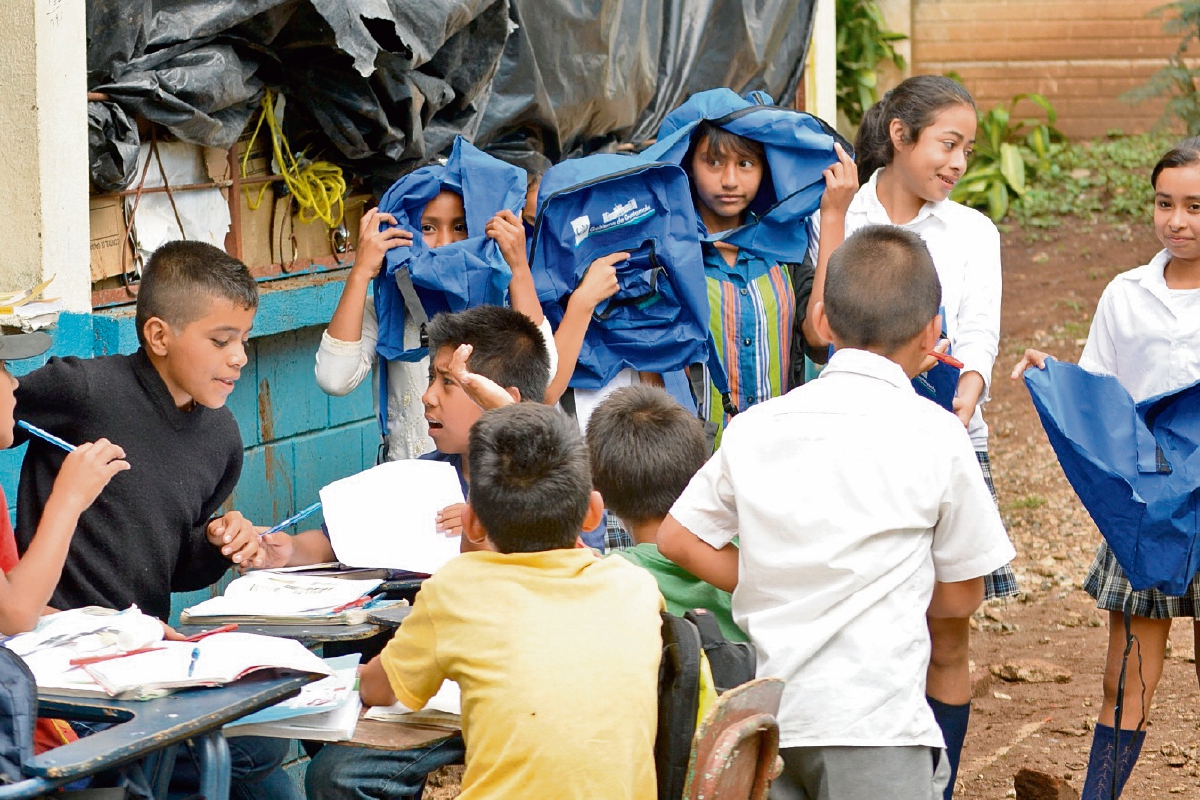 Estudiantes de  la escuela de la aldea El Pino, Barberena, muestran mochilas rotas. (Foto Prensa Libre: Oswaldo Cardona)