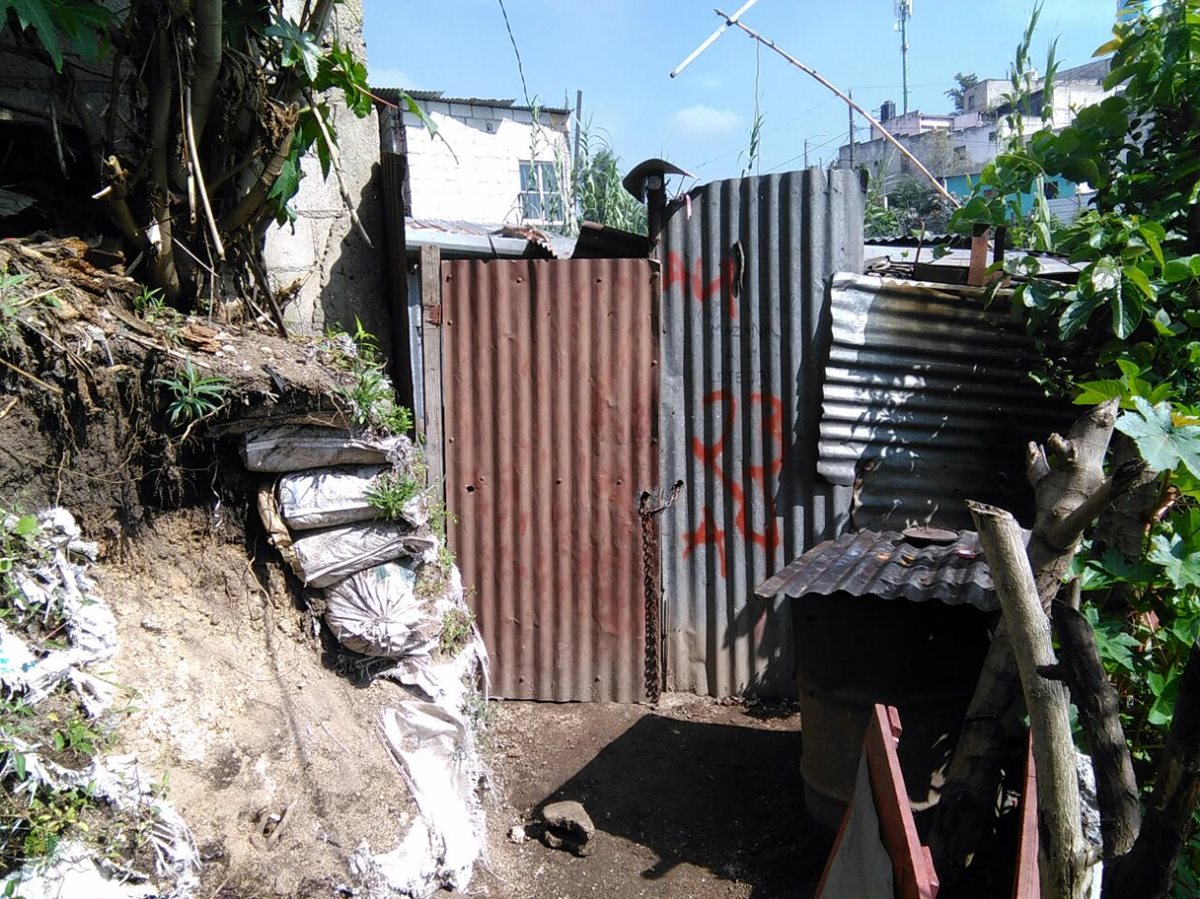 La puerta de la casa donde vivía la familia masacrada ayer en la noche, permanece cerrada. Investigadores buscan evidencias. (Foto Prensa Libre: Estuardo Paredes)