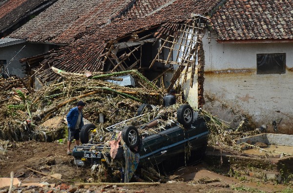 Un hombre inspecciona un vehículo dañado por la inundación en Garut, Java, Indonesia. (Foto Prensa Libre: AP)